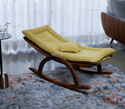 Yellow rocking chair in a room with a patterned rug and curtains.