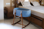Blue baby crib with wooden frame in a bedroom setting
