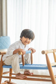 Child sitting on a wooden chair with a blue seat
