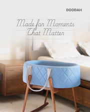Blue baby bassinet with wooden legs in a bedroom setting